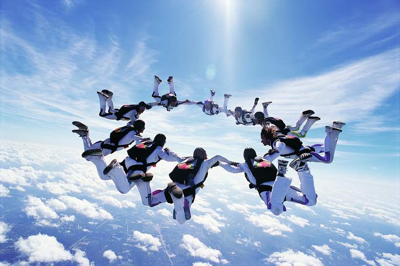 A team in freefall formation against a bright sky.